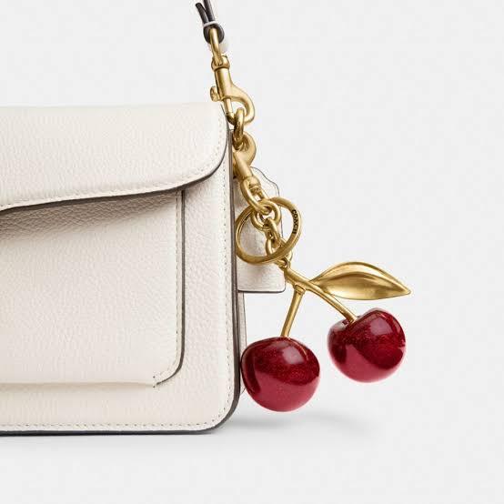 White leather bag with gold cherry keychain, minimalist fashion accessory from Blissbymi