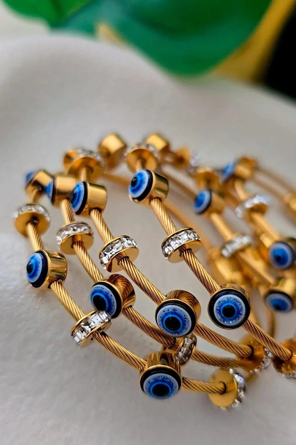 Gold cable bracelets with blue evil eye charms and crystal accents from Bliss Bymi jewelry