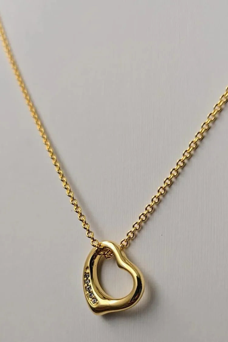 Gold heart pendant necklace with crystal details on a plain background, Bliss Bymi jewelry