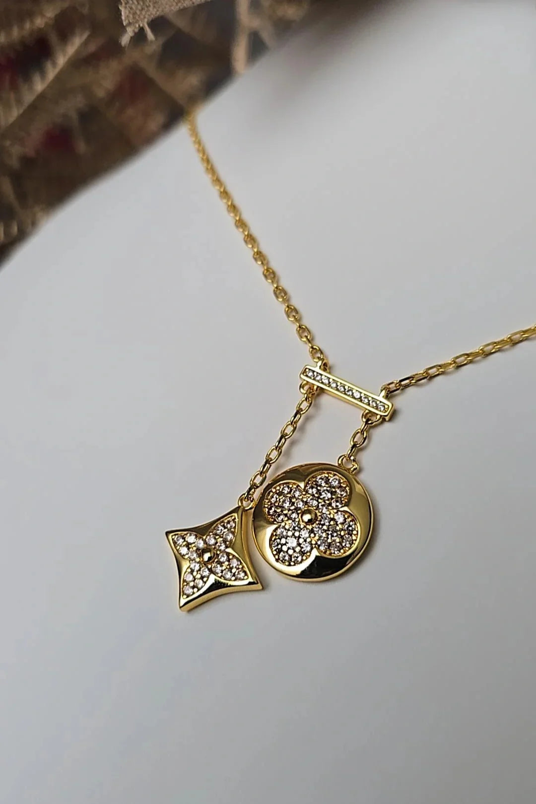 Gold chain necklace with two crystal-studded geometric pendants on white background, Blissbymi jewelry