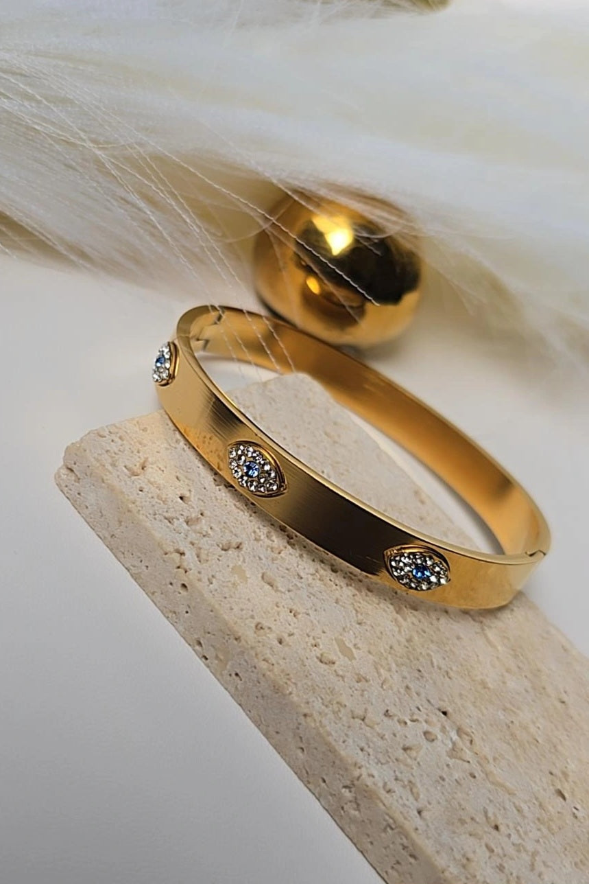 Gold bracelet with embedded stones on a textured surface