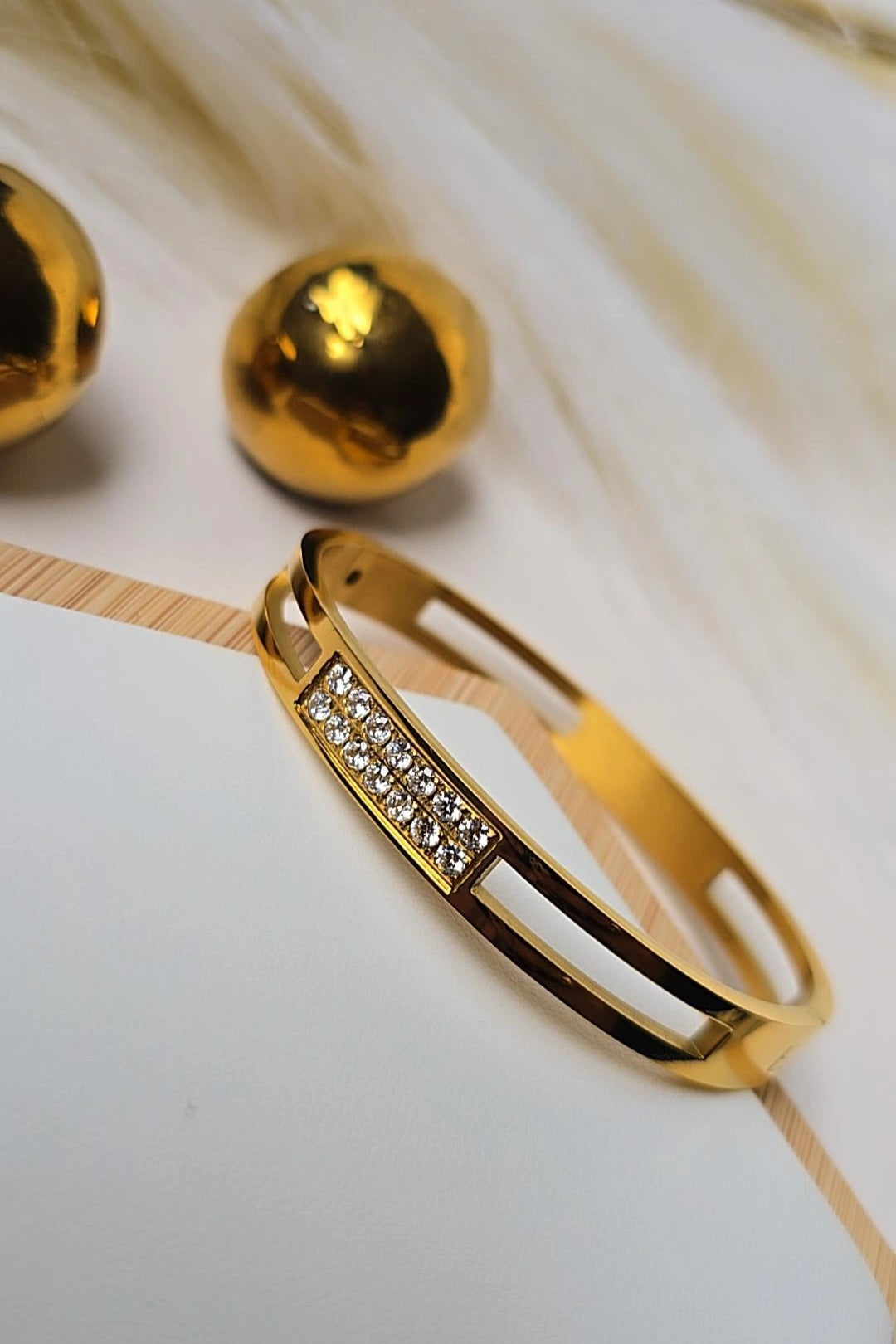 Gold bracelet with embedded stones on a light background