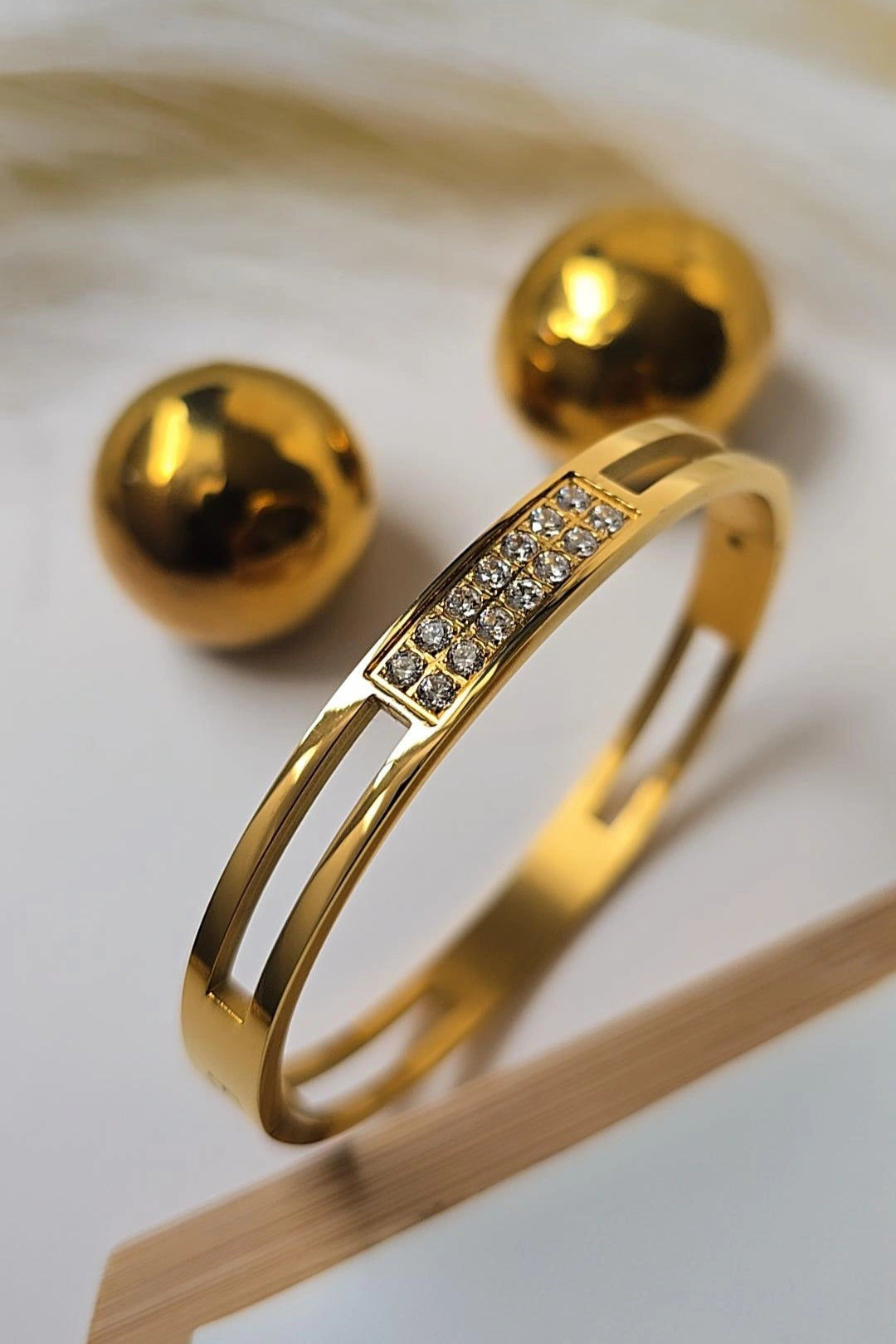 Gold bracelet with embedded diamonds on a white background
