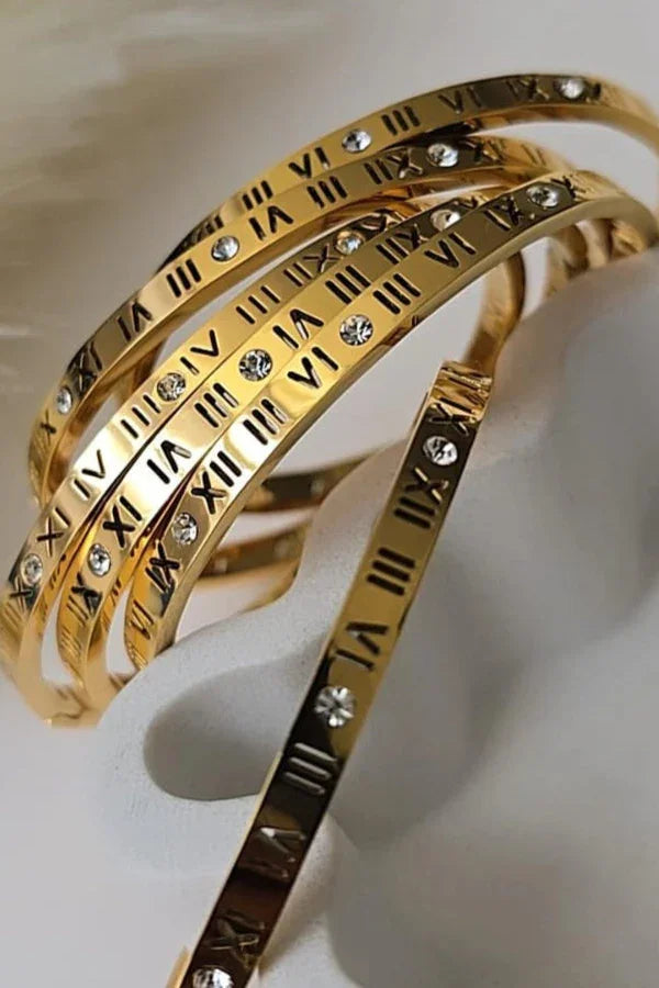 Gold Blissbymi bracelets with Roman numerals and embedded crystals, elegant jewelry.