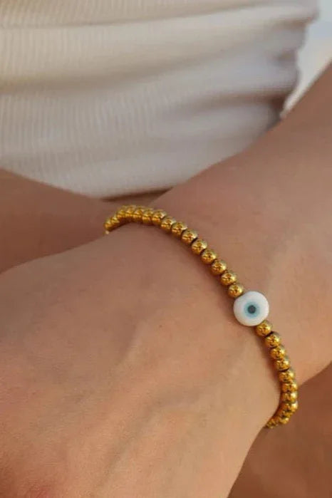 Gold beaded evil eye bracelet on wrist, minimalist jewelry by Bliss Bymi