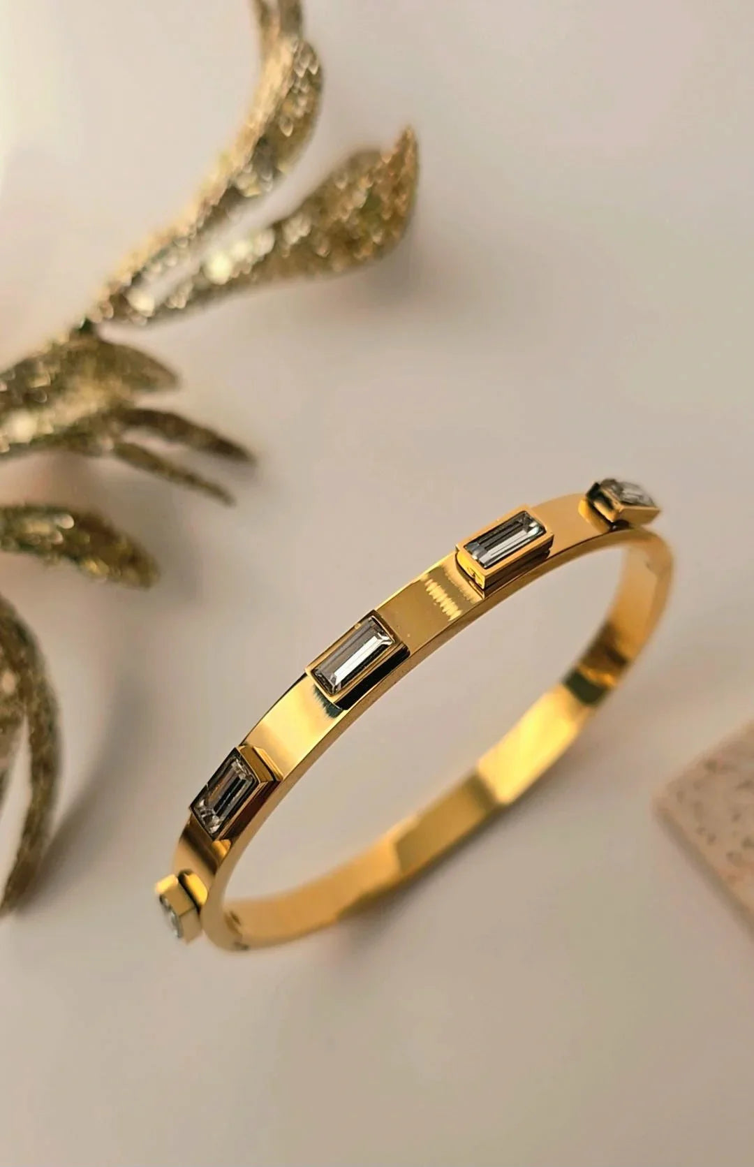 Gold bangle bracelet with rectangular crystals on white background, Blissbymi jewellery