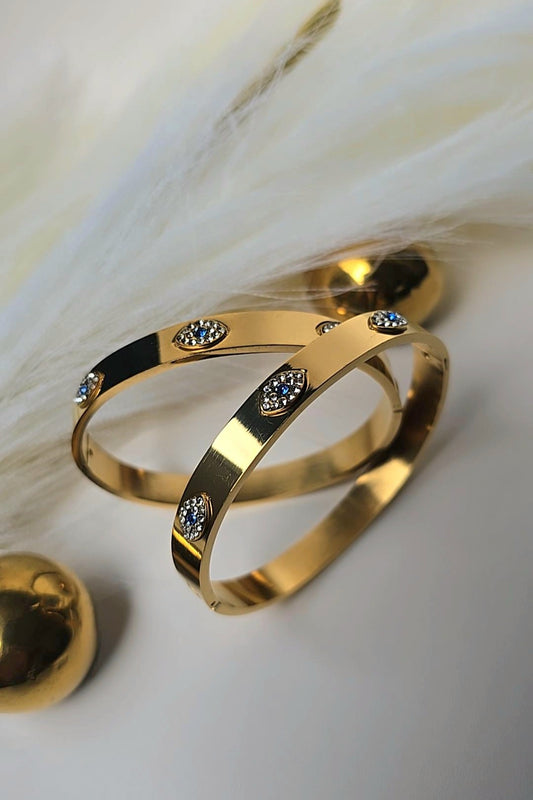 Gold bracelet with embedded stones on a soft white background
