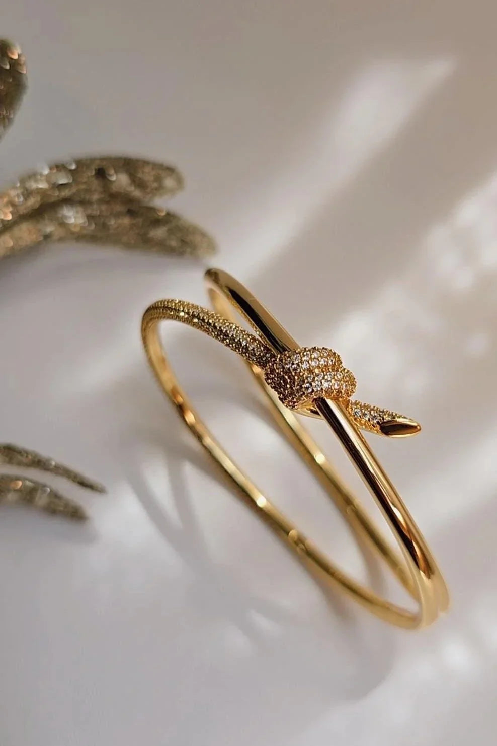 Gold snake-shaped bracelet with crystal accents from Bliss Bymi on a light background